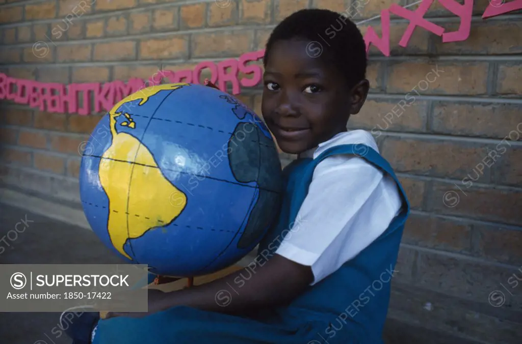 Malawi, Blantyre, Portrait Of Child Holding Papier Mache Globe Teaching Aid Made By Pamet From Recycled Materials.