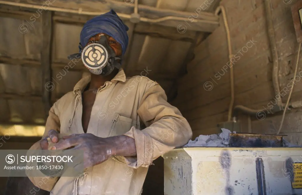 Malawi, Dedza, Dedza Potteries Producing Fair Trade Goods For Export.  Craftsman Wearing Protective Mask And Overalls To Grind Rock.
