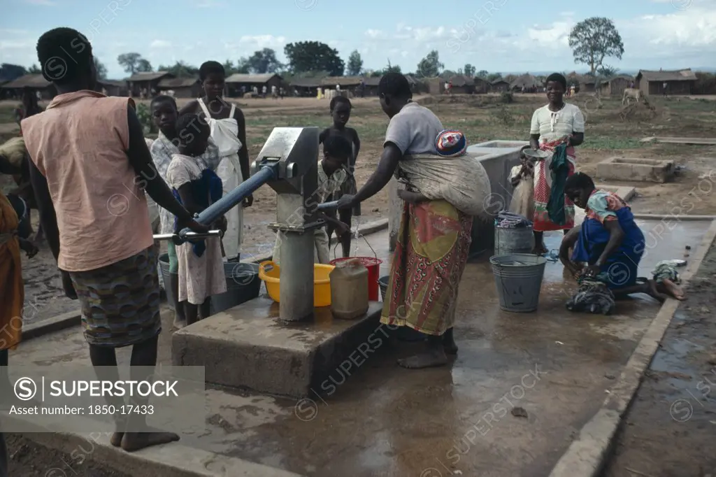 Malawi, Refugees, Mozambican Women And Children At Water Pump In Refugee Camp.