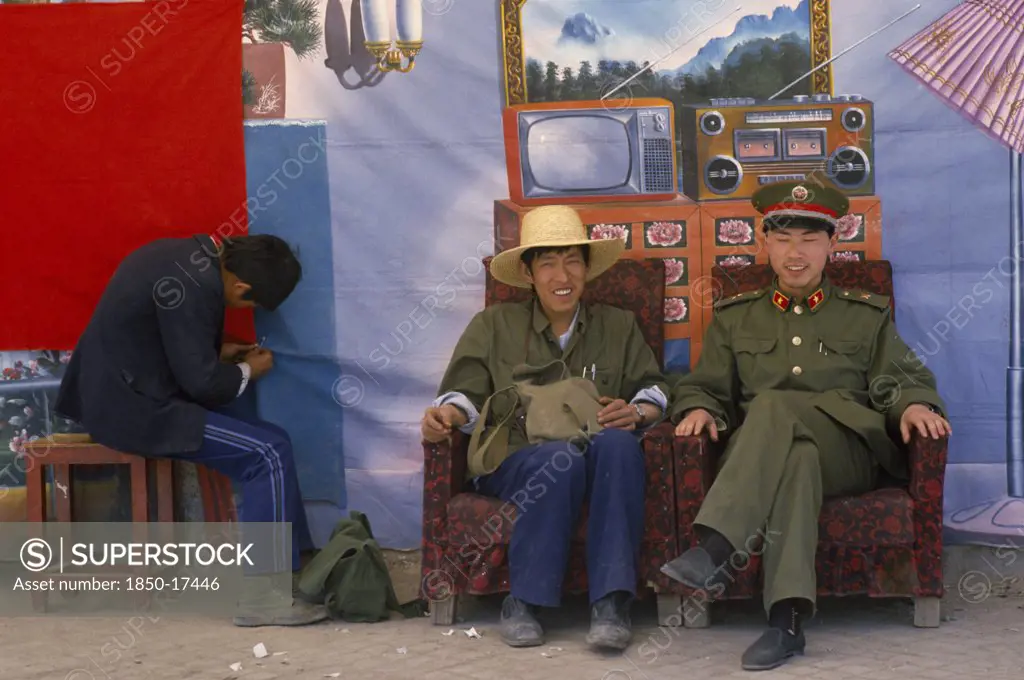 Tibet, Lhasa, 'Chinese Police Pose In Front Of Backdrop Featuring Desirable Electrical Goods In Domestic Interior, Equipment They Are Unlikely To Have In Reality.'