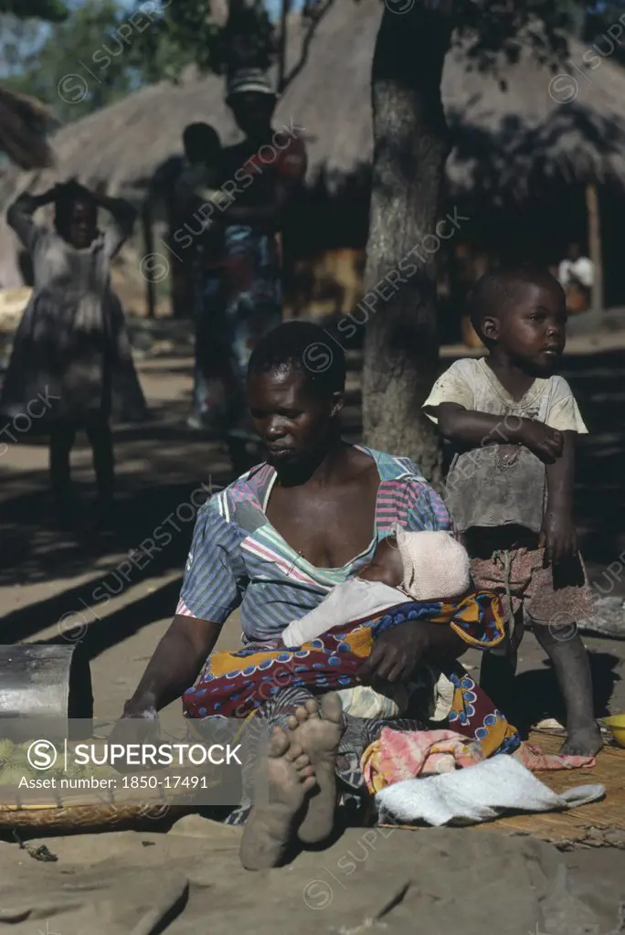 Zambia, Ukwimi Settlement, Mozambique Refugee Woman And Children With Basket Of Fruit.