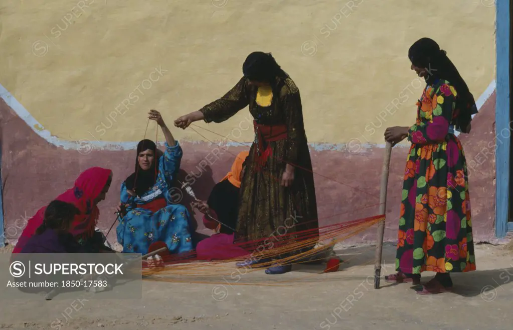 Egypt, Western Desert, Bedouin, Group Of Bedouin Women In Colourful Dress Weaving And Spinning Coloured Yarn.