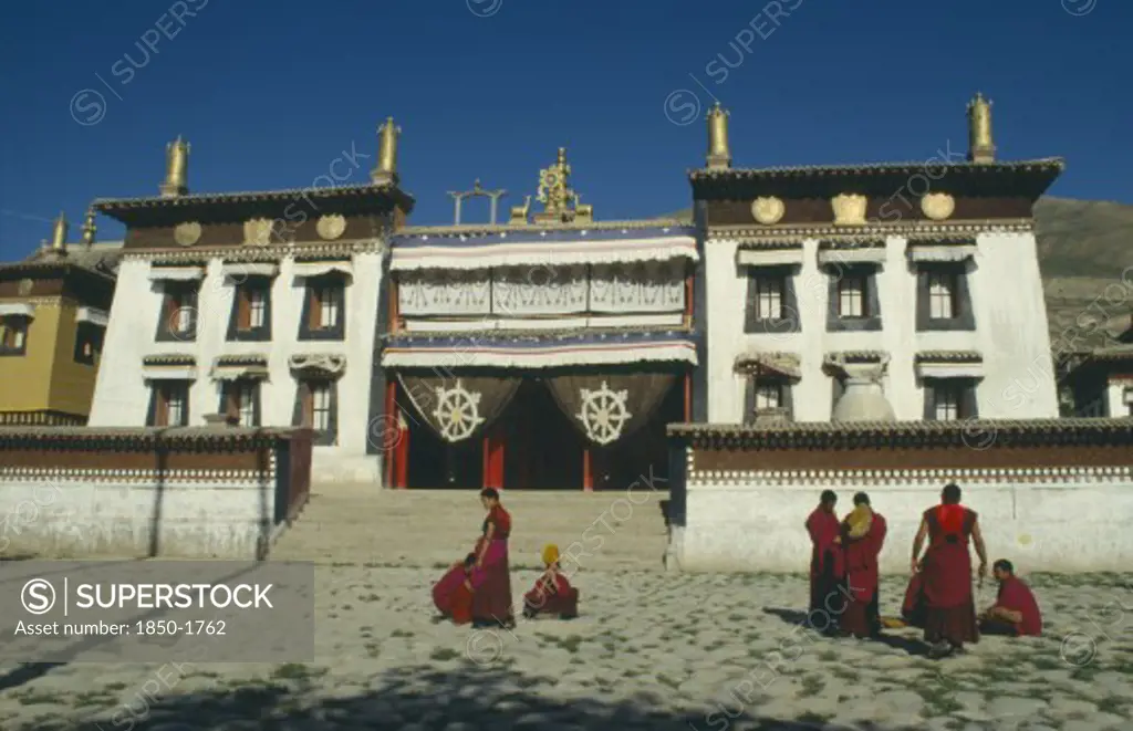 China, Qinghai, Tongren , Tibetan Monastery With Monks Gathered Outside