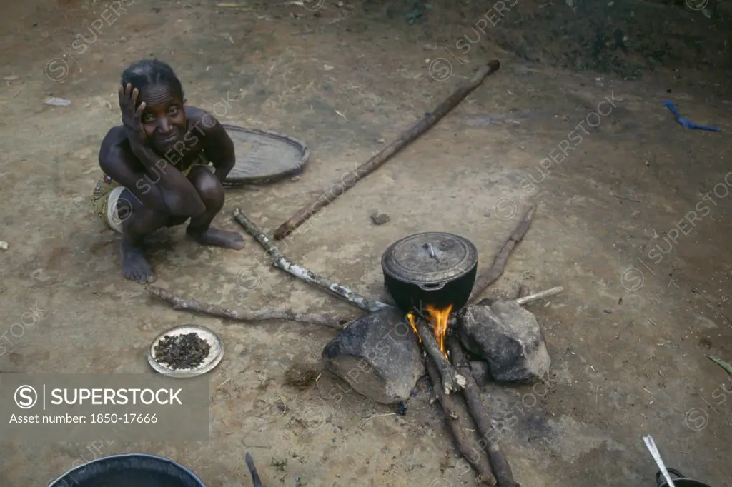 Liberia, People, Woman Cooking On Open Fire With Cooking Pot Balanced On Stones.