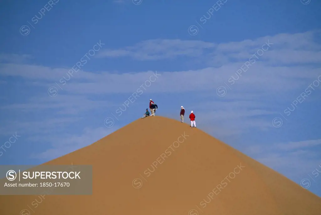 Libya, Sahara Desert, Tourists Standing On Top Of Saharan Sand Dune.