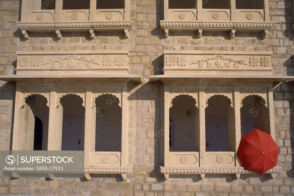 India, Rajasthan, Jaisalmer, Hotel Himmatgarth Palace Exterior With Detail Of Windows And A Red Unbreller