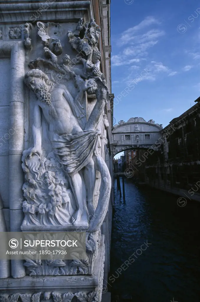 Italy, Veneto, Venice, The Doges Palace. Relief Carving Of The Drunkenness Of Noah Or The Vine Angle On The Corner Of Building Beside The Bridge Of Sighs With Water Below