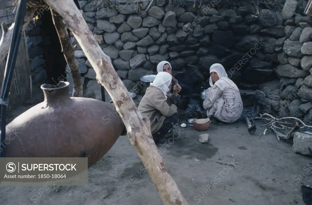 Turkey, East, Nemrut, Women Sitting On Ground Beside Suspended Vessel Used To Churn Milk.