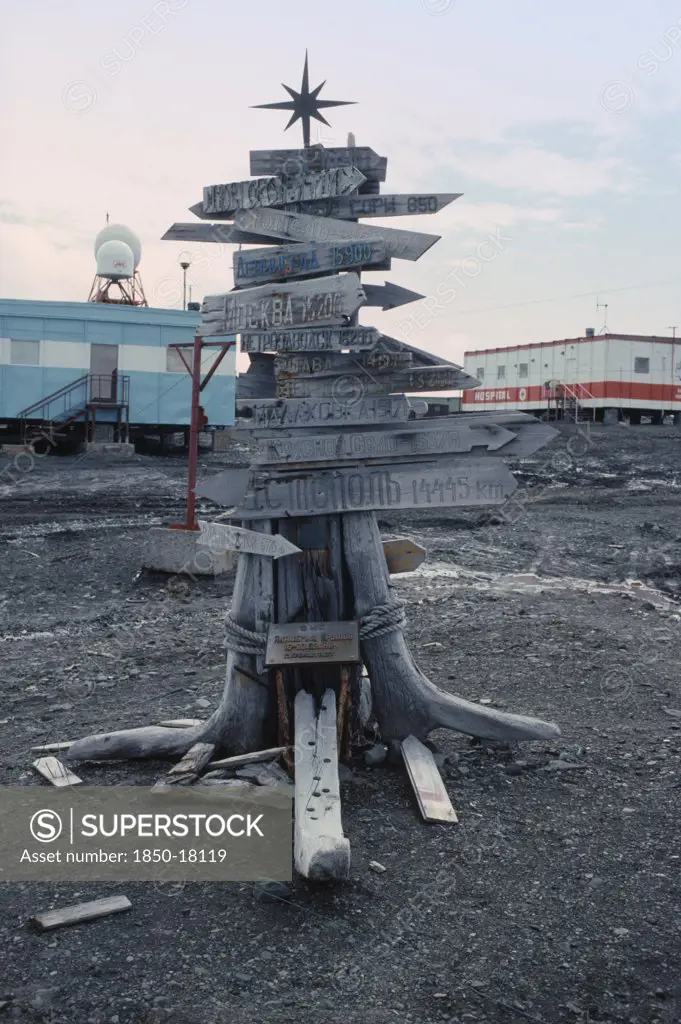 Antarctica, King George Island, Russian Bellingshausen Station. Wooden Sign Post With Star On Top With Arrows Pointing To The Distance Home To Russia