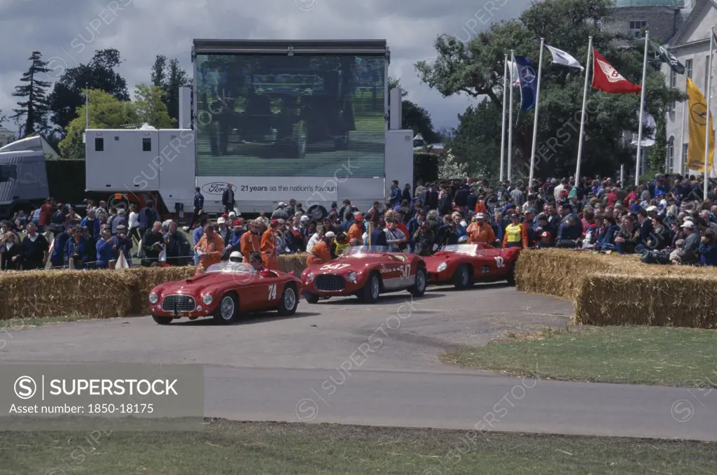 England, West Sussex, Goodwood, Festival Of Speed. Three Red Ferraris 2 Litre Built In 1950 4.1 Litre 1953 And 4.1Litre 1957. Crowds Of Spectators Gathered Around Circuit