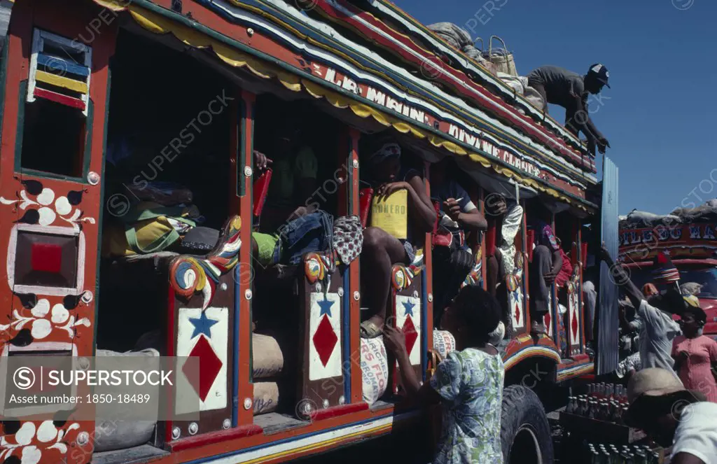 Haiti, Transport, Colourfully Painted Bus With People Loading Goods Onto The Roof