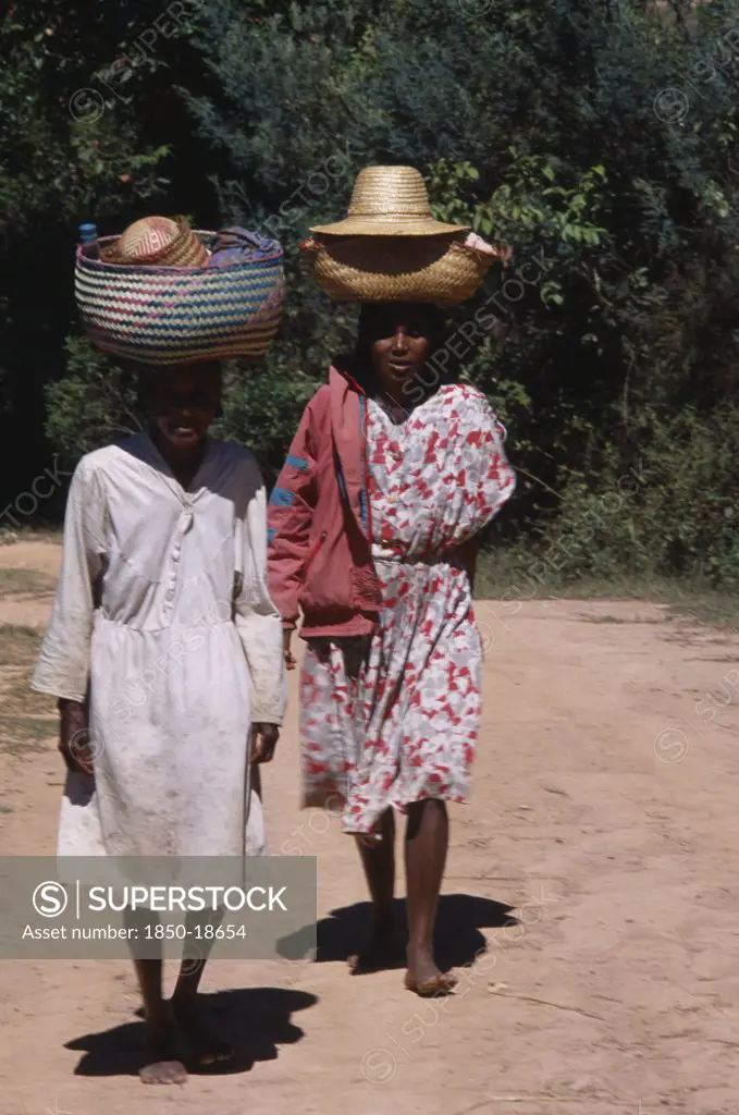 Madagascar, People, Women, Near Ambositra. Two Barefooted Women Walking Up A Dirt Track Carrying Wicker Baskets On Their Heads