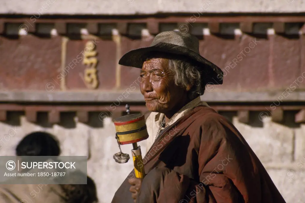 China, Tibet, Lhasa, An Elderly Pilgrim With Prayer Wheel In The Barkhor Bazaar