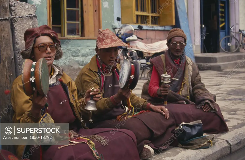 China, Tibet, Lhasa, Monk Musicians Sat Playing In The Barkhor Bazaar.