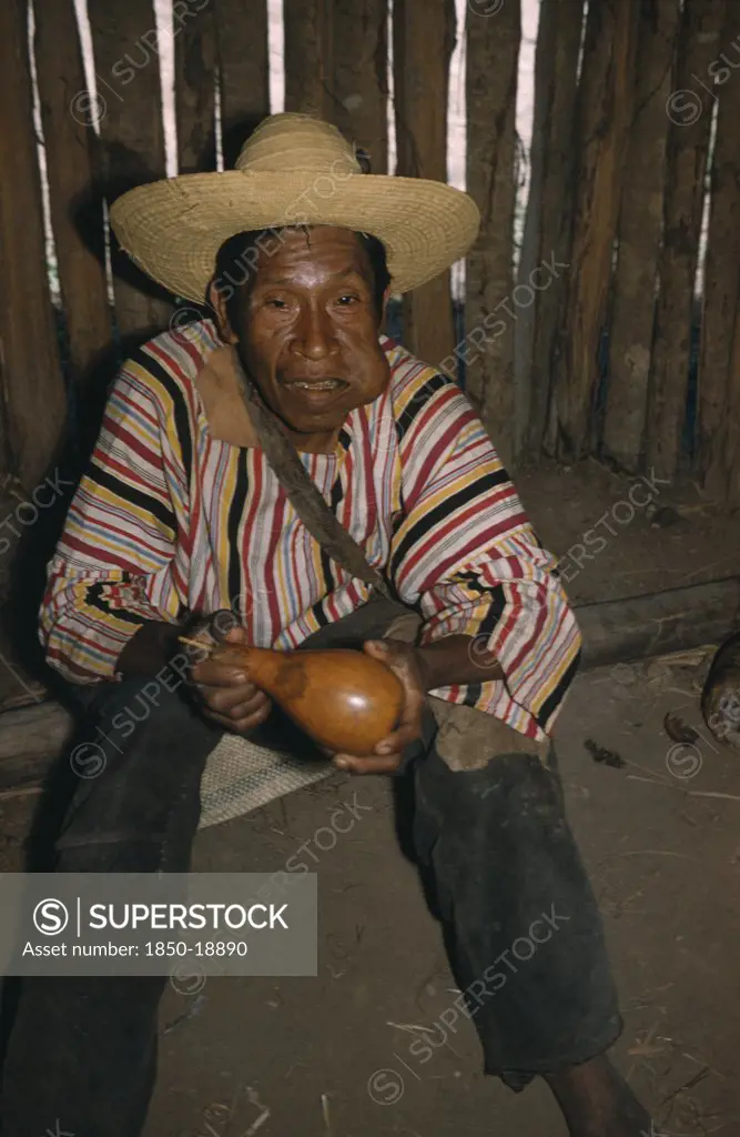 Colombia, Sierra De Perija, Yuko - Motilon , 'Marty, An Old Man, Wearing A Local Peasant Straw Hat And Indian Woven Striped Manta  / Cloak. Chewing A Wad Of Coca Leaves, Holding A Gourd For Lime Powder (The Catalyst For Coca, Which Releases A V.Small Amount Of Alkaloid Cocaine)'
