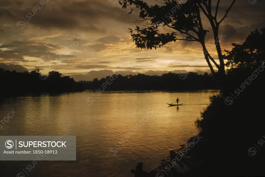 Colombia, Choco Region, Noanama Tribe, Boy Paddling Canoe On Lower Rio San Juan At Sunset
