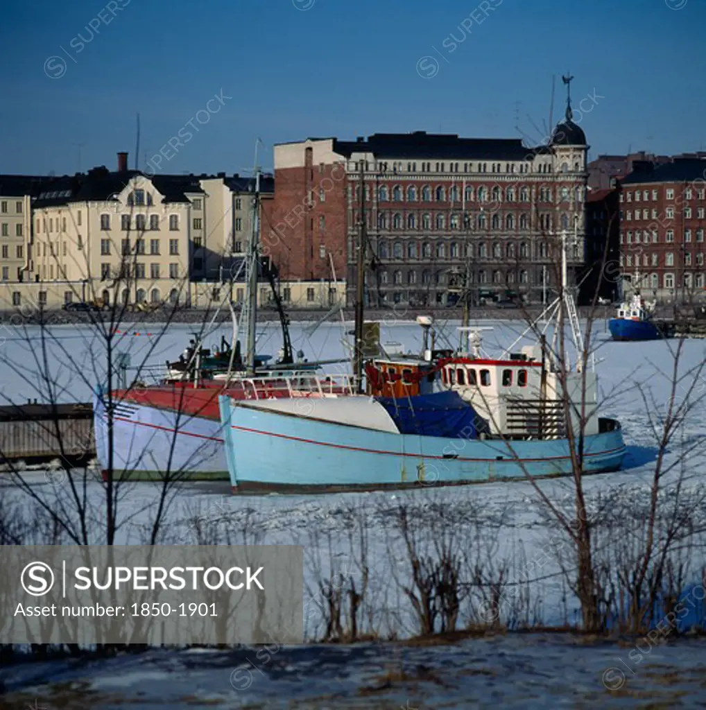 Finland, Uusimaa, Helsinki, 'North Harbour,Fishing Boats,Frozen Sea,Buildings Beyond '
