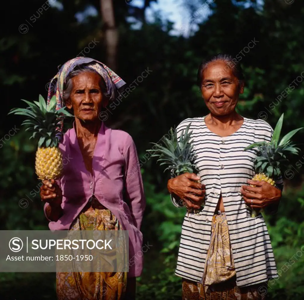 Indonesia, Lombok, Batu Layar, Two Ladies Near Senggigi Holding Pineapples