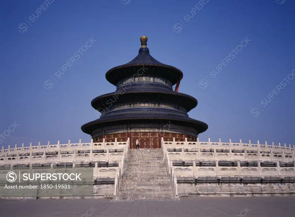 China, Beijing, Temple Of Heaven.  Hall Of Prayer For Good Harvests With Western Tourist Standing At Top Of Steps To Entrance.