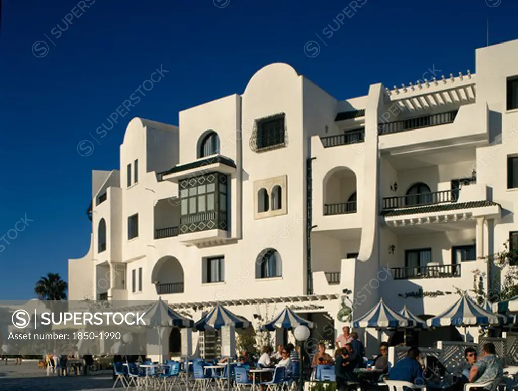 Tunisia, Port El Kantaoui , Villas In An Arab Style. Tourists Sitting At Tables Outside Cafe On Cobbled Street