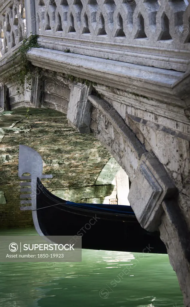 Italy, Veneto, Venice, The Ferro At The Bow Of A Gondola Passing Under A Footbridge Over A Canal