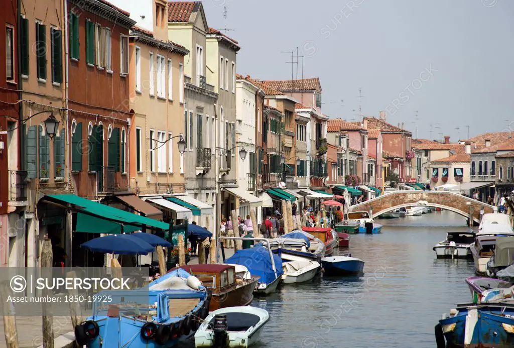 Italy, Veneto, Venice, The Main Canal Beside Fondamente Dei Vetrai On Murano Island With Boats Moored At The Quayside And A Bridge Across The Canal