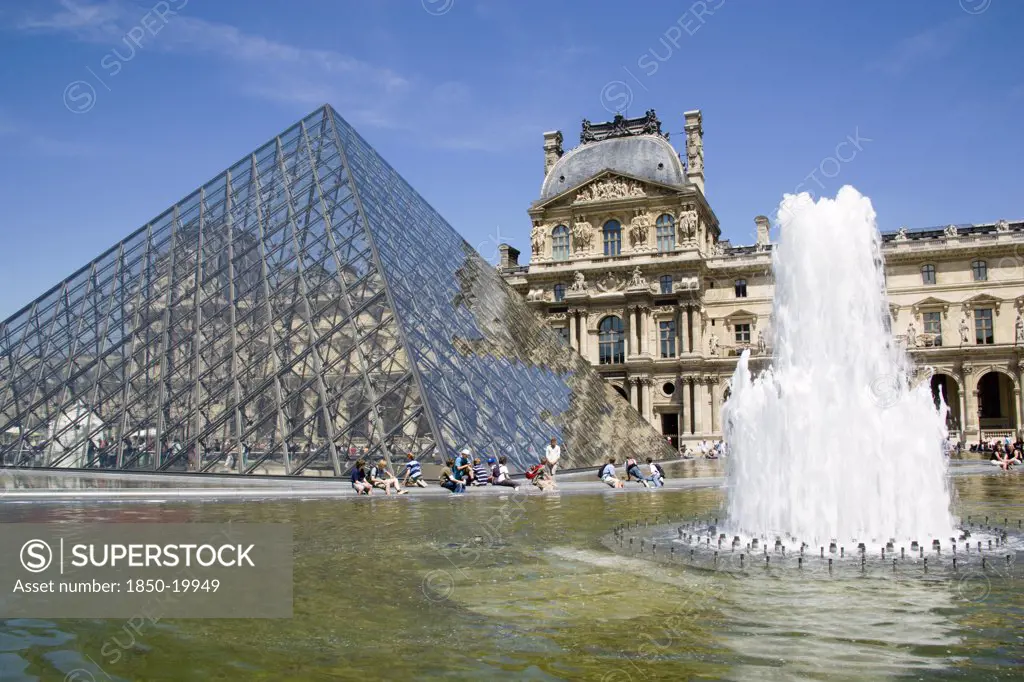 France, Ile De France, Paris, Tourists Sitting Beside The Fountain Pools In The Cour Napoleon At The Musee Du Louvre With The Pyramid Entrance Designed By I M Pei And The Richelieu Pavilion Beyond
