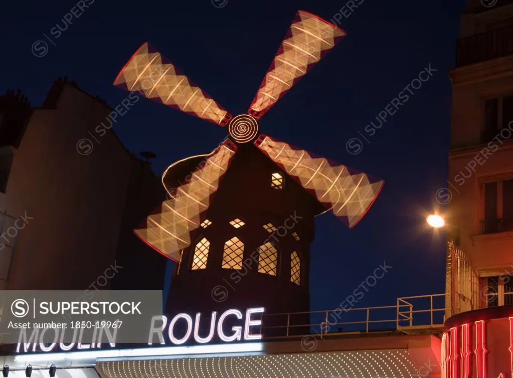 France, Ile De France, Paris, Montmartre The Moulin Rouge Nightclub Illuminated At Night With The Windmill Sails Rotating