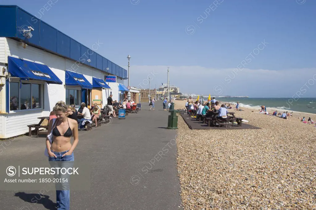 England, East Sussex, Brighton, Girl Walking Past The Babylon Lounge Bar On The Seafront At Hove.