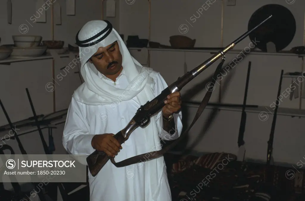 Qatar, Doha, Man Holding An Old Rifle In Doha Museum