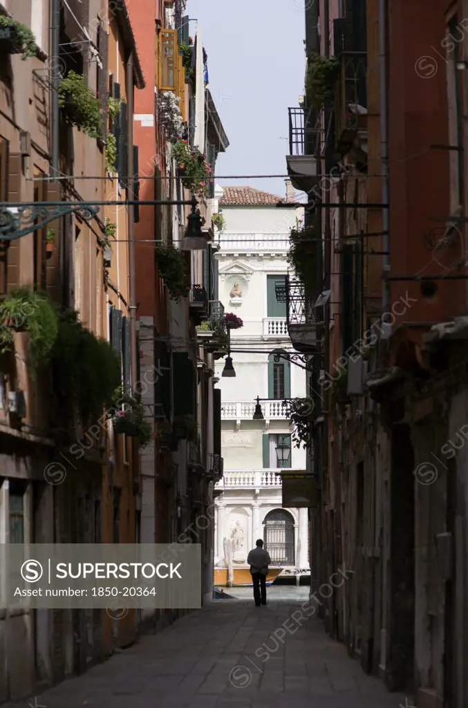 Italy, Veneto, Venice, View Down A Narrow Street To The Grand Canal In The San Polo And Santa Croce District With A Man In Silhouette By The Canal