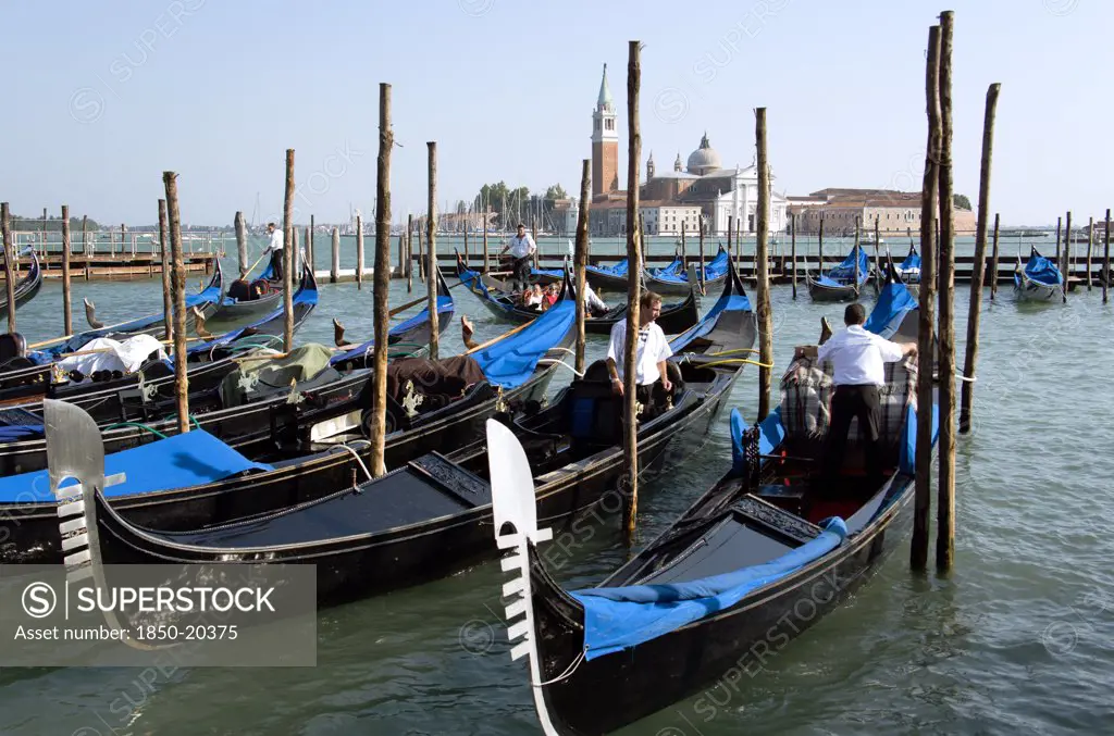 Italy, Veneto, Venice, Gondoliers Prepare Gondolas In The Molo San Marco Basin In Front Of Palladio'S Church Of San Giorgio Maggiore On The Island Of The Same Name