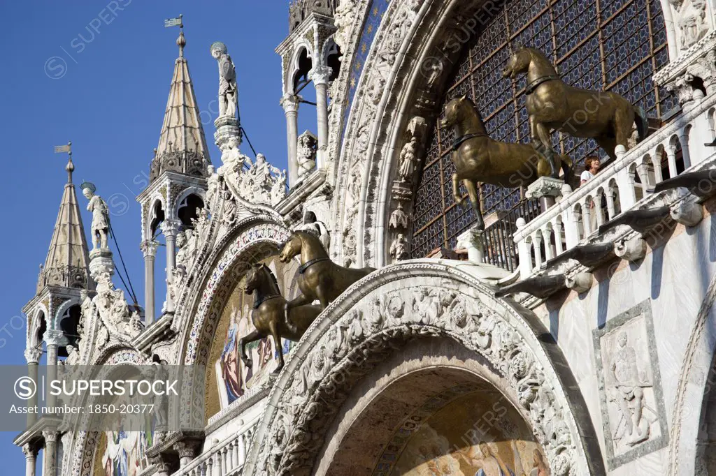 Italy, Veneto, Venice, The Bronze Horses Of St Mark And The 17Th Century Mosaics On The Facade Of St Marks Basilica With Tourists On The Viewing Balcony