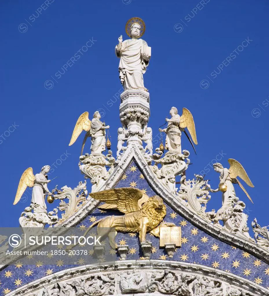 Italy, Veneto, Venice, 'The 15Th Century Statues Of St Mark And Angels Over The Central Arch Of St Marks Basilica. The Winged Lion Of St Mark, The Symbol Of Venice, Stands Below The Saint'