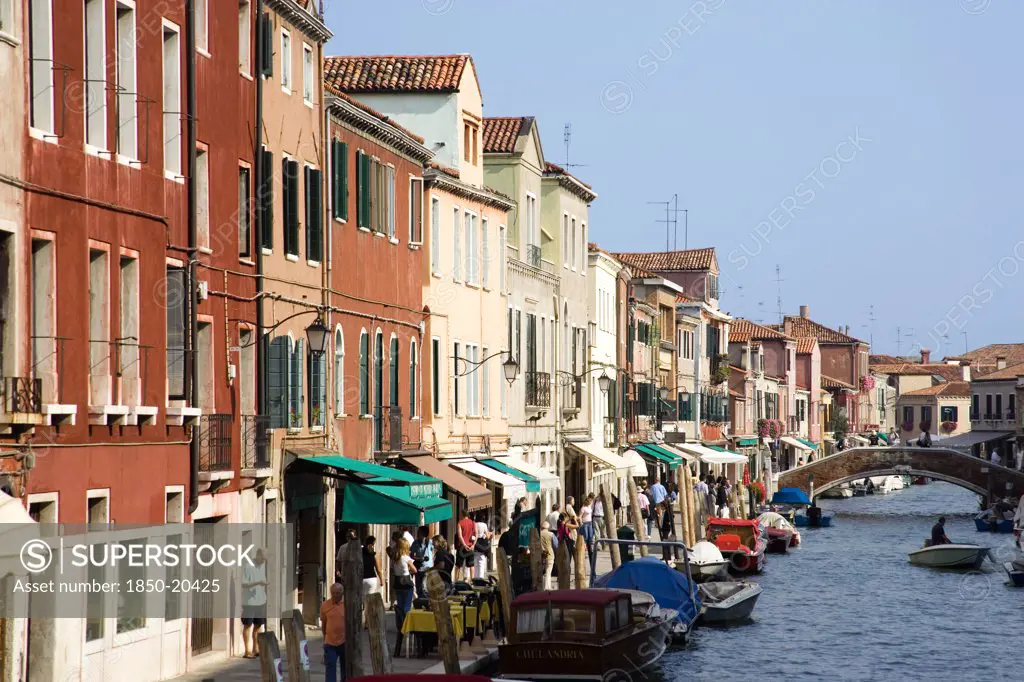 Italy, Veneto, Venice, Tourists Walking Along The Fondamenta Dei Vetrai With Boats Moored On The Rio Dei Vetrai Canal On The Lagoon Island Of Murano