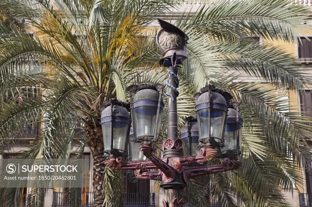 Spain, Catalonia, Barcelona, Ornate street lamp and palm trees in Placa Reial.