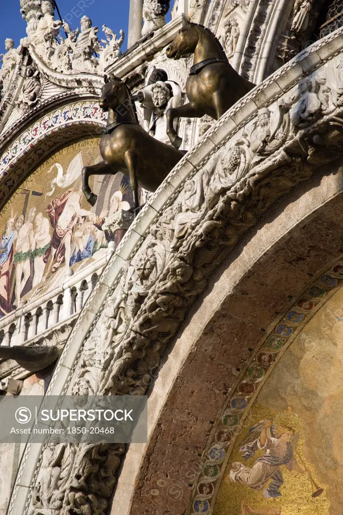 Italy, Veneto, Venice, Two Of The Four Bronze Horses Of St Mark Above The Central Doorway On The Facade Of The Basilica Can Marco With Its 17Th Century Religious Mosaics