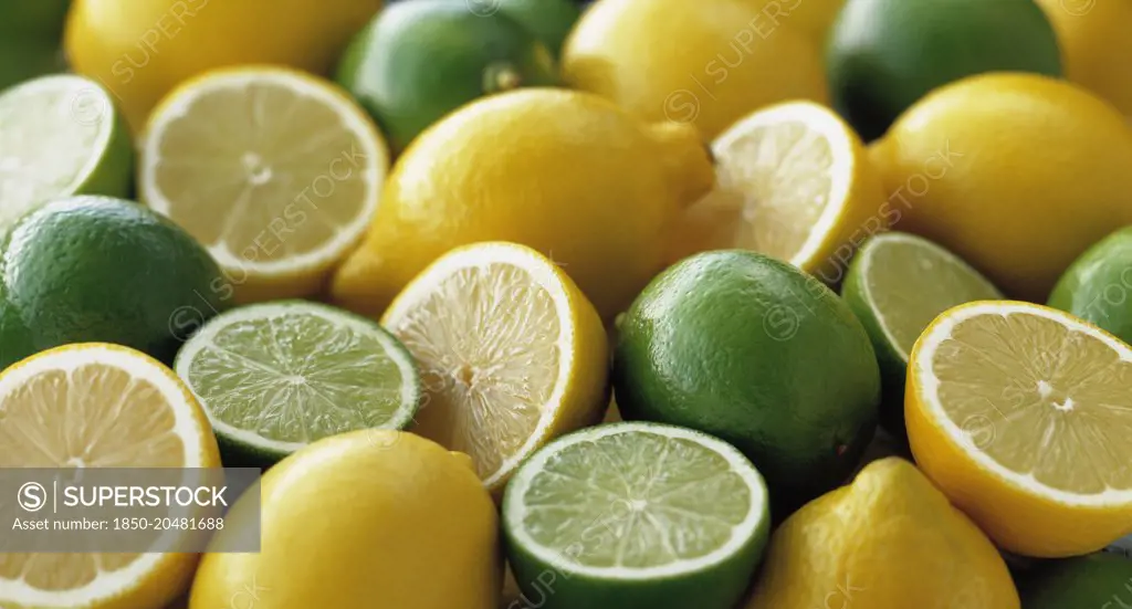 Lemon, Citrus limon and limes, Citrus aurantiifolia, Several whole fruits, with halves grouped together.