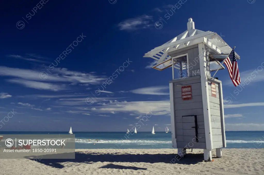 Usa, Florida, Fort Lauderdale Beach, Lifeguard Tower Displaying American Flag With Sailboats Seen On Turquoise Sea Behind