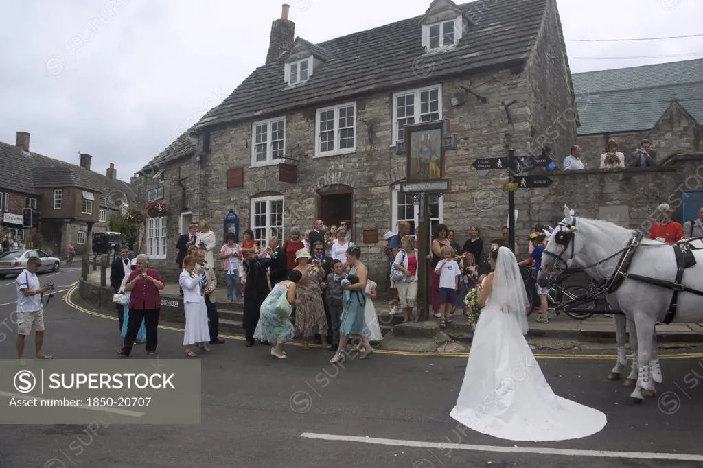 England, Dorset, Corfe, A Wedding Party Gathered On The Street Taking Photographs Of The Bride Near A Shire Horse