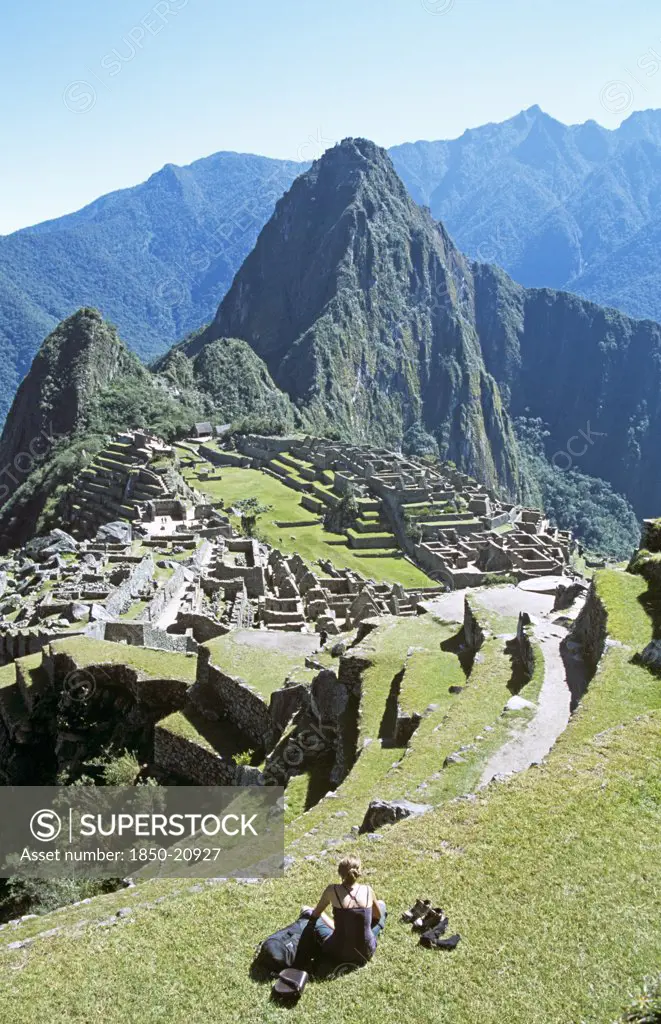 Peru, Cusco Department, Machu Picchu, 'Inca Ruins, Terraces, Visitor Sitting On Terrace, And Huayna Picchu.'