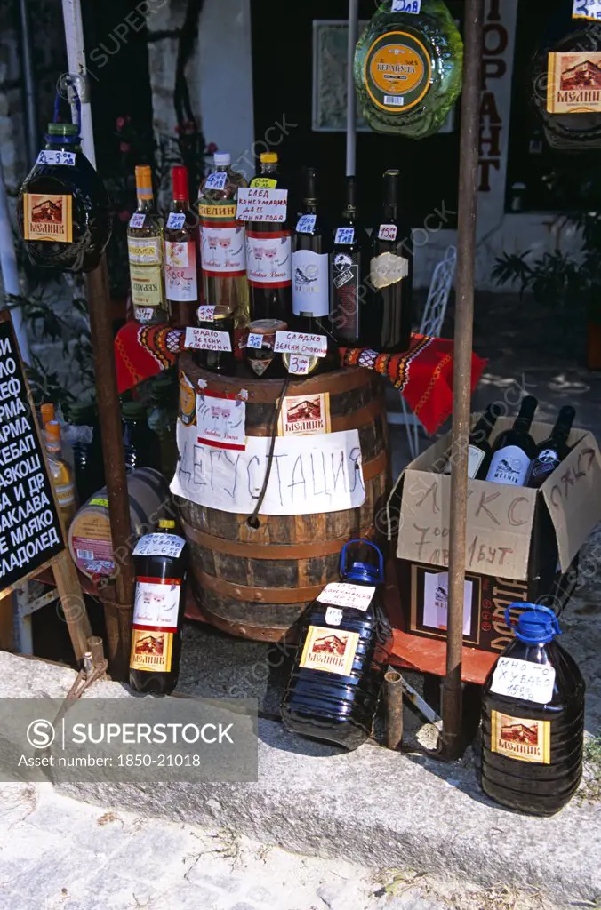Bulgaria, Melnik., 'Display Of Wine Bottles, Barrel, And Containers Outside Shop.'