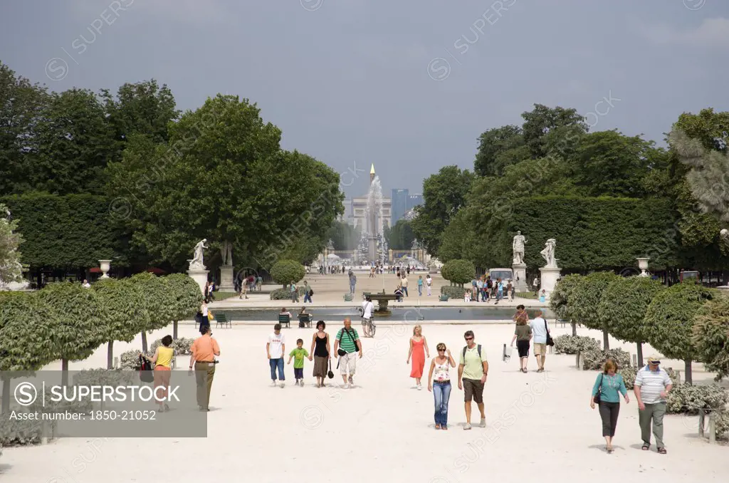 France, Ile De France, Paris, Tourists In The Jardin Des Tuileries With The Obelisk And The Arc De Triomphe In The Distance Beyond The Fountain