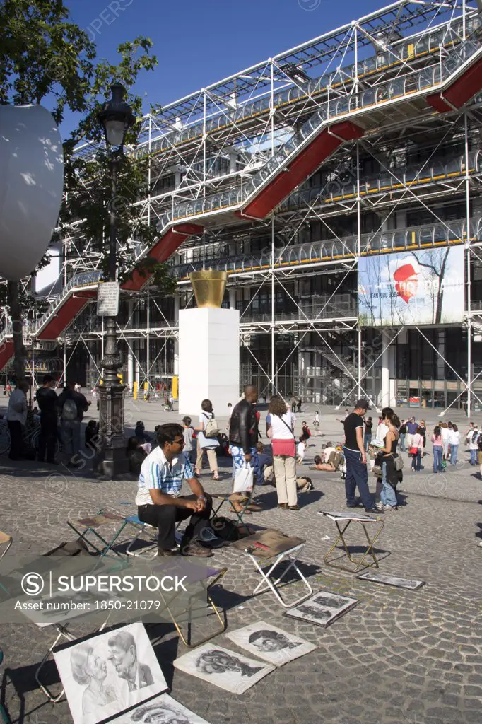 France, Ile De France, Paris, Tourists Watching A Street Performer In The Square Outside The Pompidou Centre In Beauborg Les Halles With Artists Selling Their Work On The Pavement In The Foreground