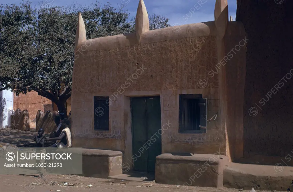 Nigeria, Kano, Traditional Mud Brick Hausa Dwelling With Men And Boy Beside Exterior Wall.