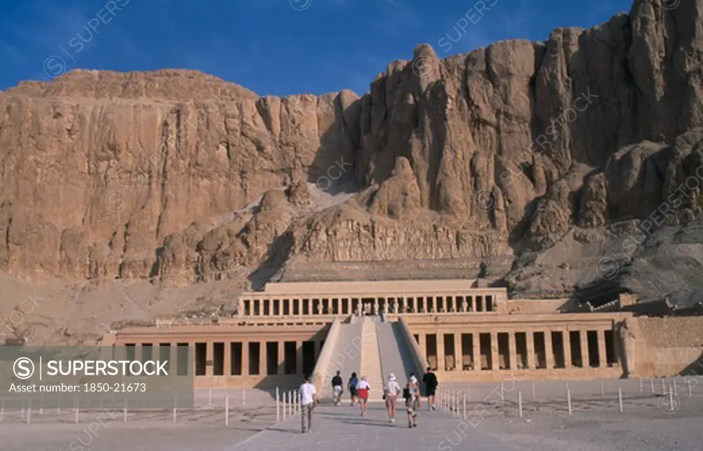 Egypt, Nile Valley, Thebes, Deir El-Bahri. Hatshepsut Mortuary Temple. Visitors Walking Towards Ramped Entrance With Limestone Cliffs Behind.