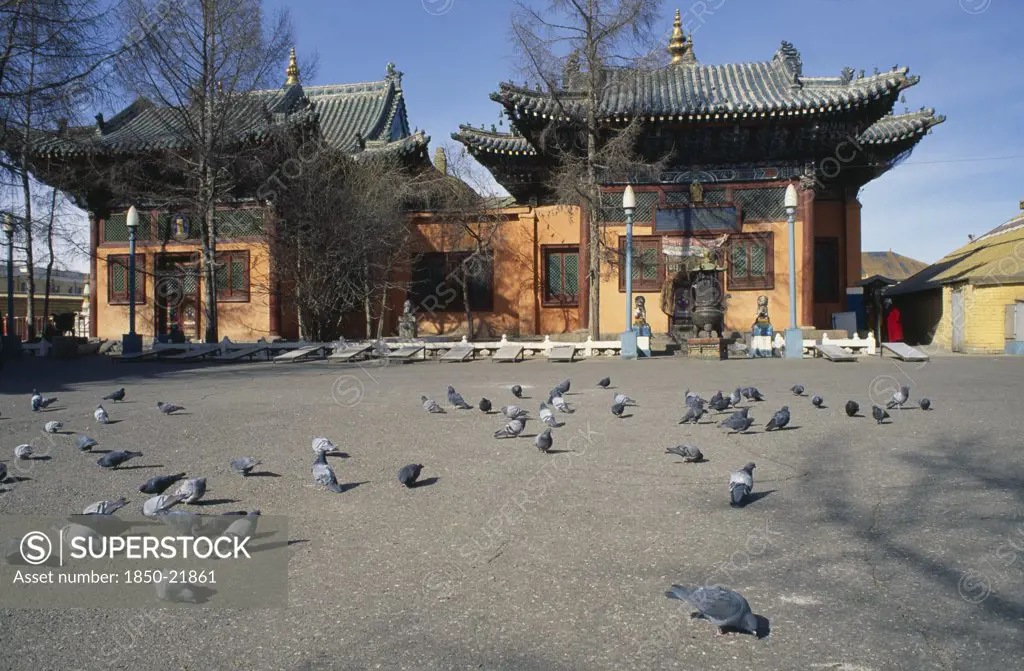 Mongolia, Ulaan Baatar, Gandan Hiid Buddhist Monastery Exterior Facade With Pigeons In Courtyard In Foreground.