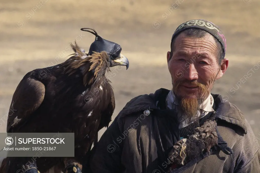 Mongolia, People, Head And Shoulders Portrait Of Kazakh Nomad Man With Golden Eagle Wearing Hood And Jesses.