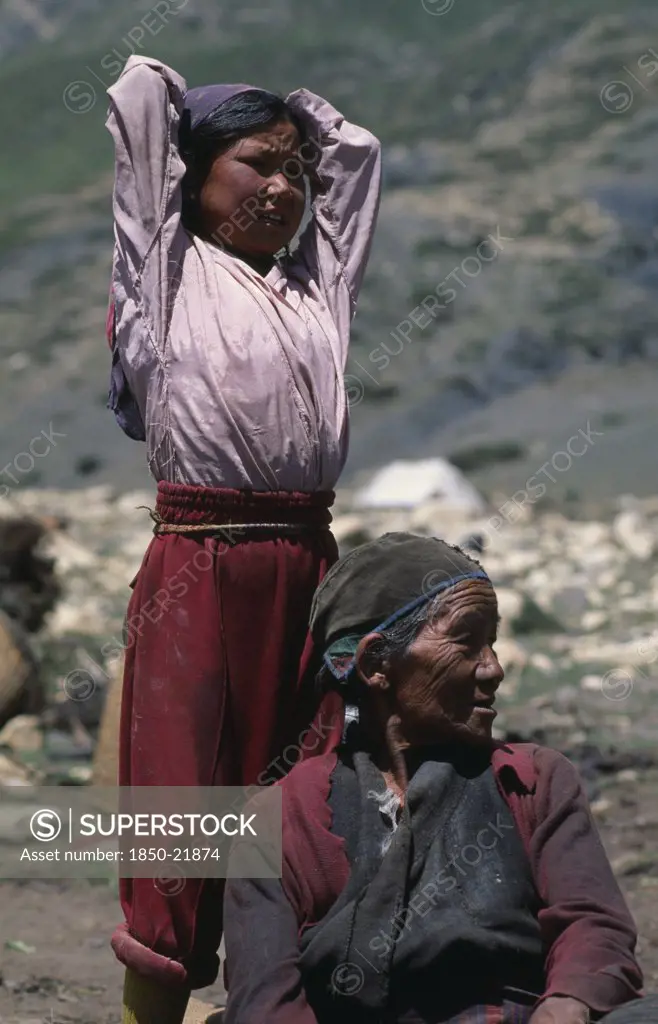 Nepal, Mustang, Nomads, 'Tibetan Nomads.  Elderly Seated Woman With Young Girl Standing Behind With Arms Raised Behind Head, Both Looking Away To Right.'