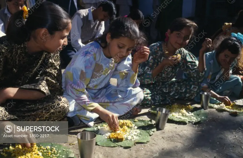India, Himachal Pradesh, Kulu, Girls Eating From Banana Leaves With Their Hands At Meal During Country Wedding.